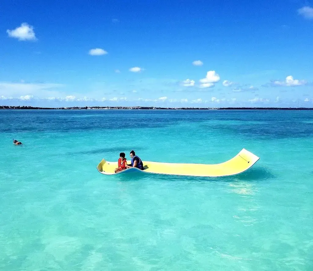 Guests on a yellow floating mat in the clear turquoise waters of Islamorada