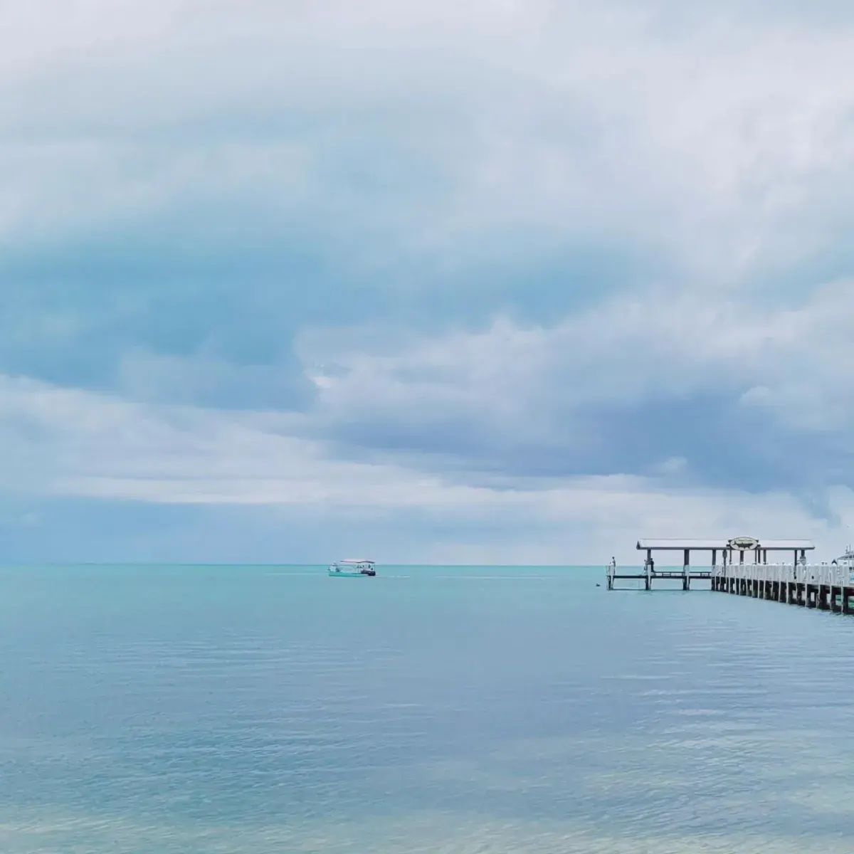 A Clearly Unique Charters boat traveling across calm blue water near a tropical dock