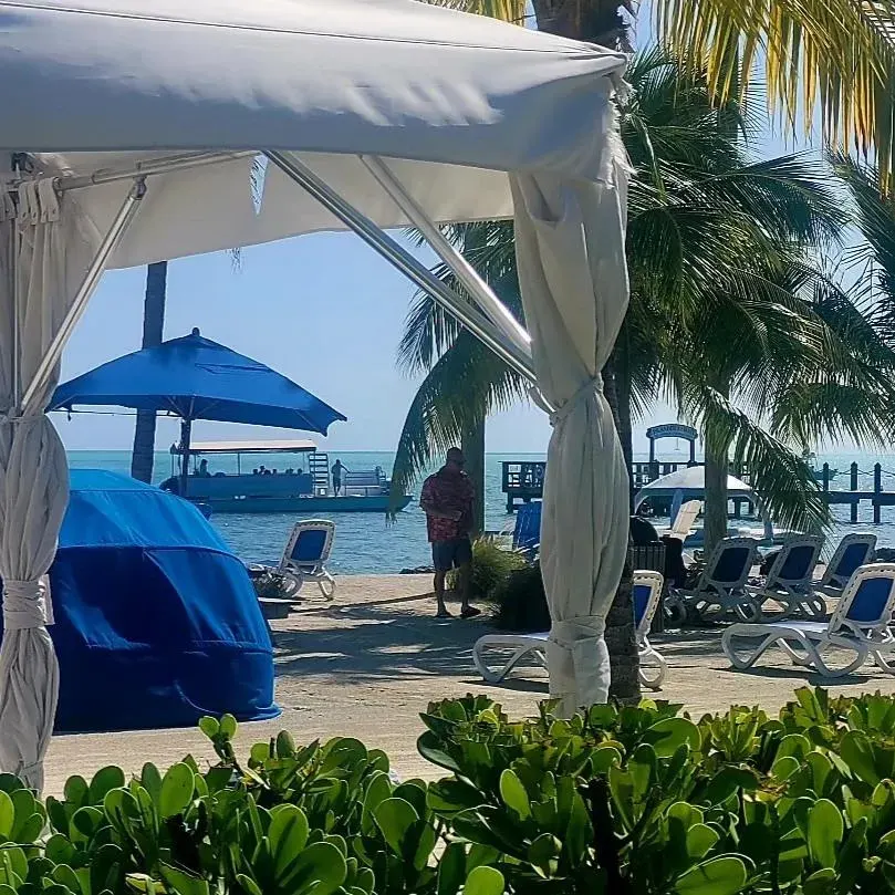 A guest smiling while enjoying a drink and floating in the clear water at an Islamorada sandbar