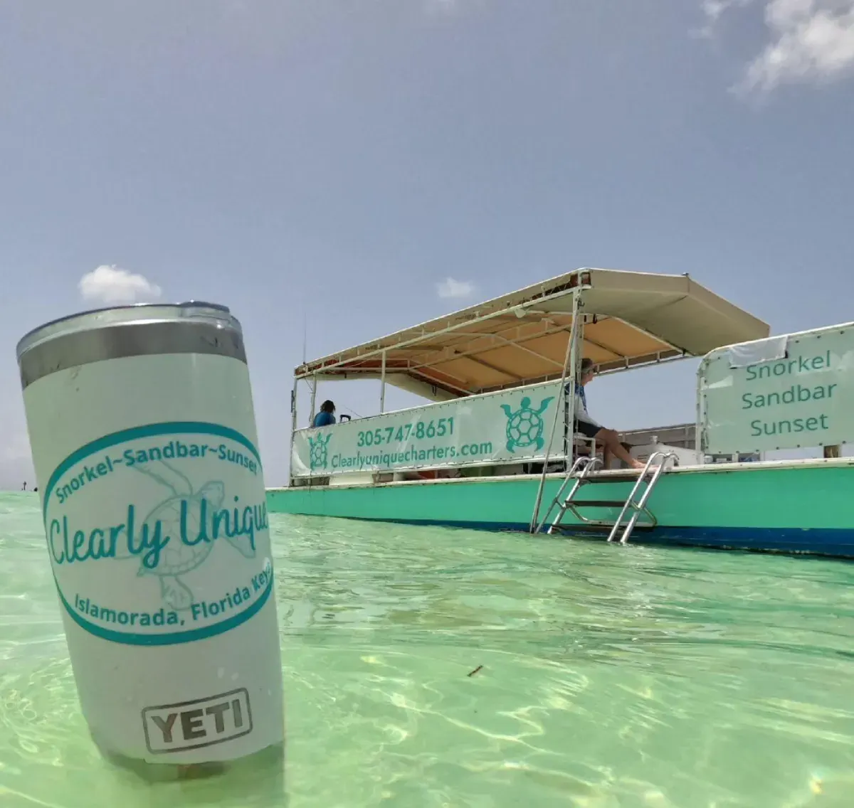 A smiling guest in a tropical sun hat enjoying a beverage while another relaxes on a floating tube in the clear Islamorada water
