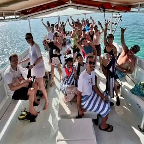 A large group of people cheering and waving from the deck of a Clearly Unique Charters boat