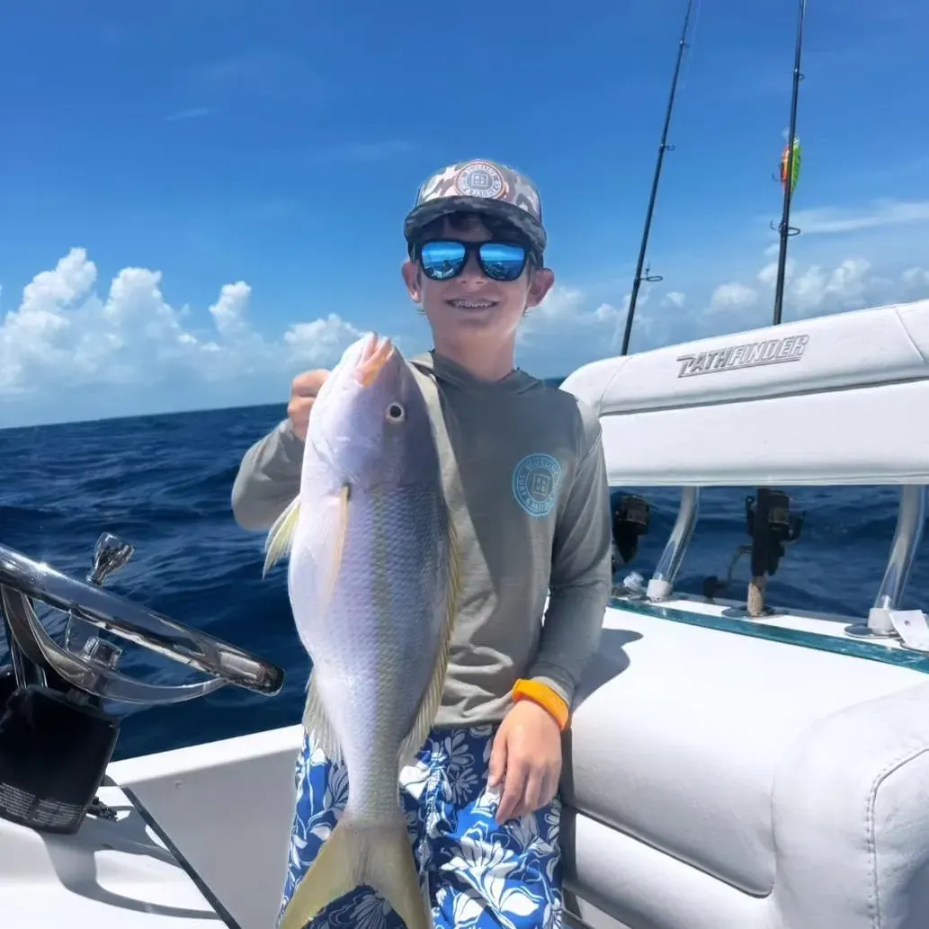 Young angler holding a freshly caught fish on a boat